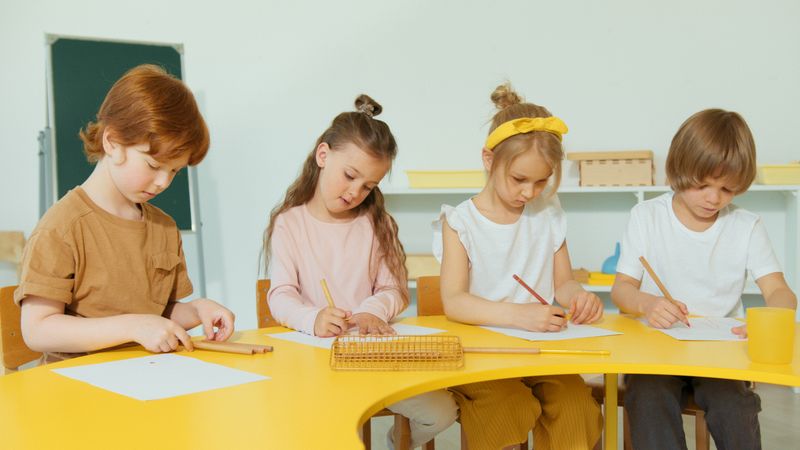 Sekelompok anak sedang menulis dan menggambar saat kegiatan belajar di kelas.