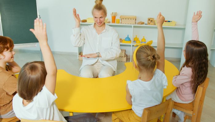 Educadora em roda com crianças em sala Montessori com materiais nas prateleiras