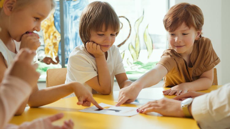 Kids Pointing Their Fingers On A Placard 