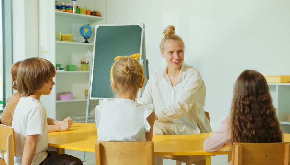 Educator greeting and supporting preschool children in a classroom setting