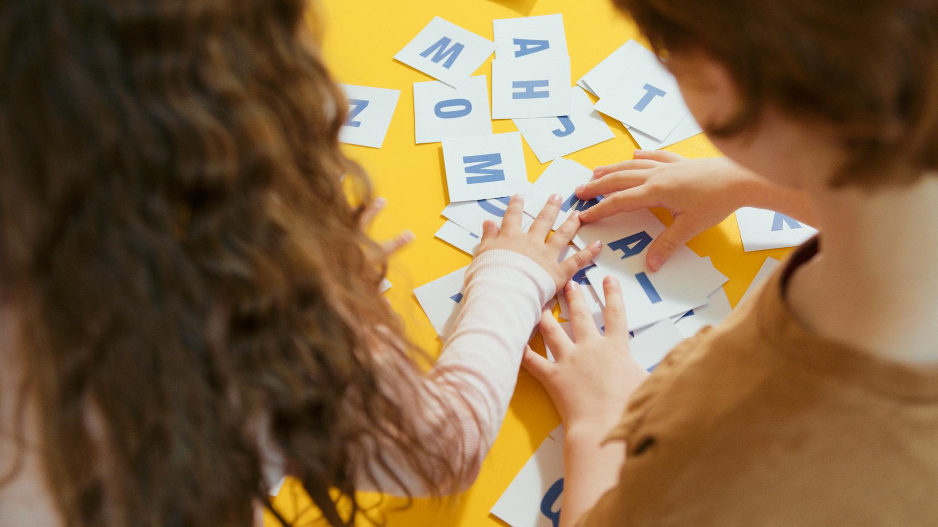Two children playing with letter cards, enhancing their learning through a fun educational activity.