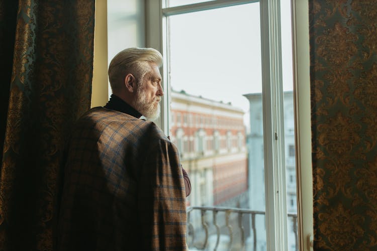 An Elderly Man Looking At The Window