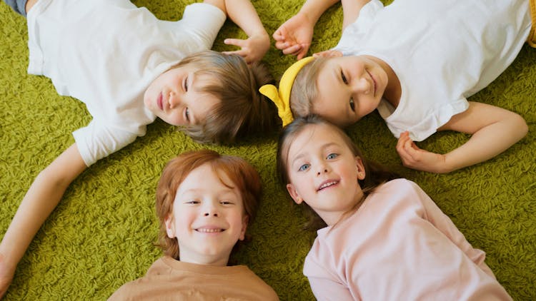 A Group Of Kids Lying On The Carpet