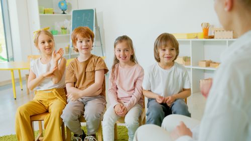 Free Group of cheerful children clapping hands in a lively classroom setting. Stock Photo