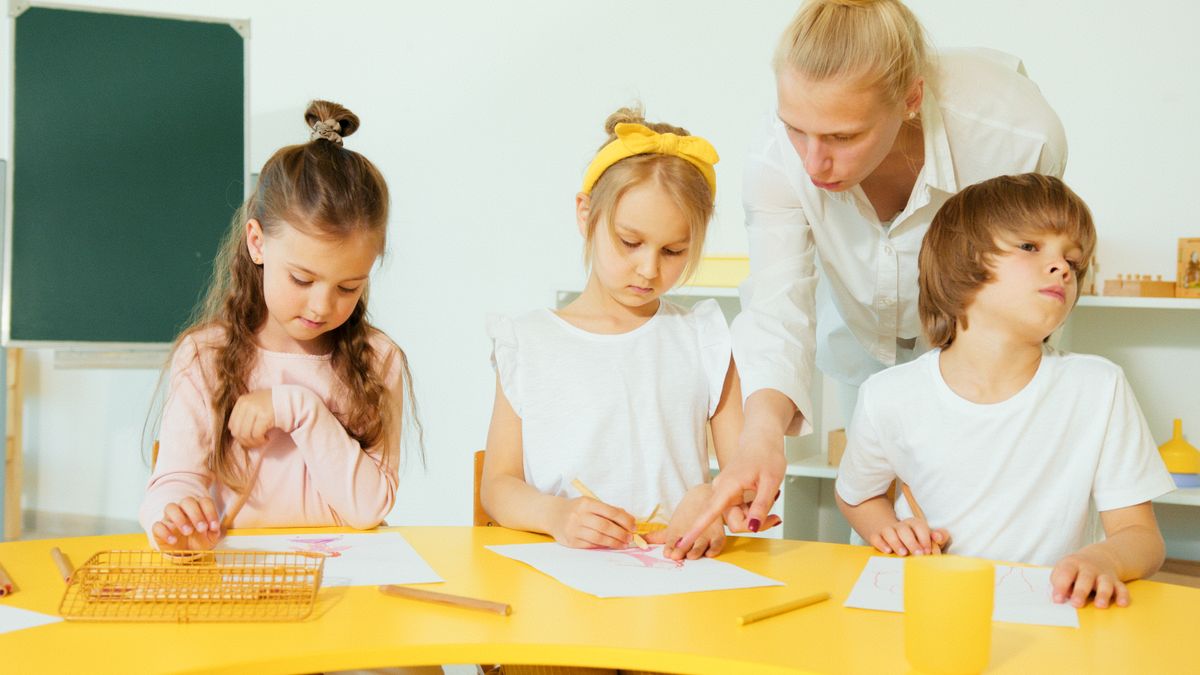 Facilitator guiding young children with drawing at a learning centre