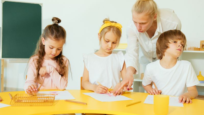 An early years practitioner helping a young child with a drawing activity