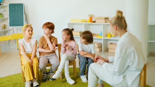 Free A group of children interacting in a classroom with their teacher, fostering learning and social skills. Stock Photo