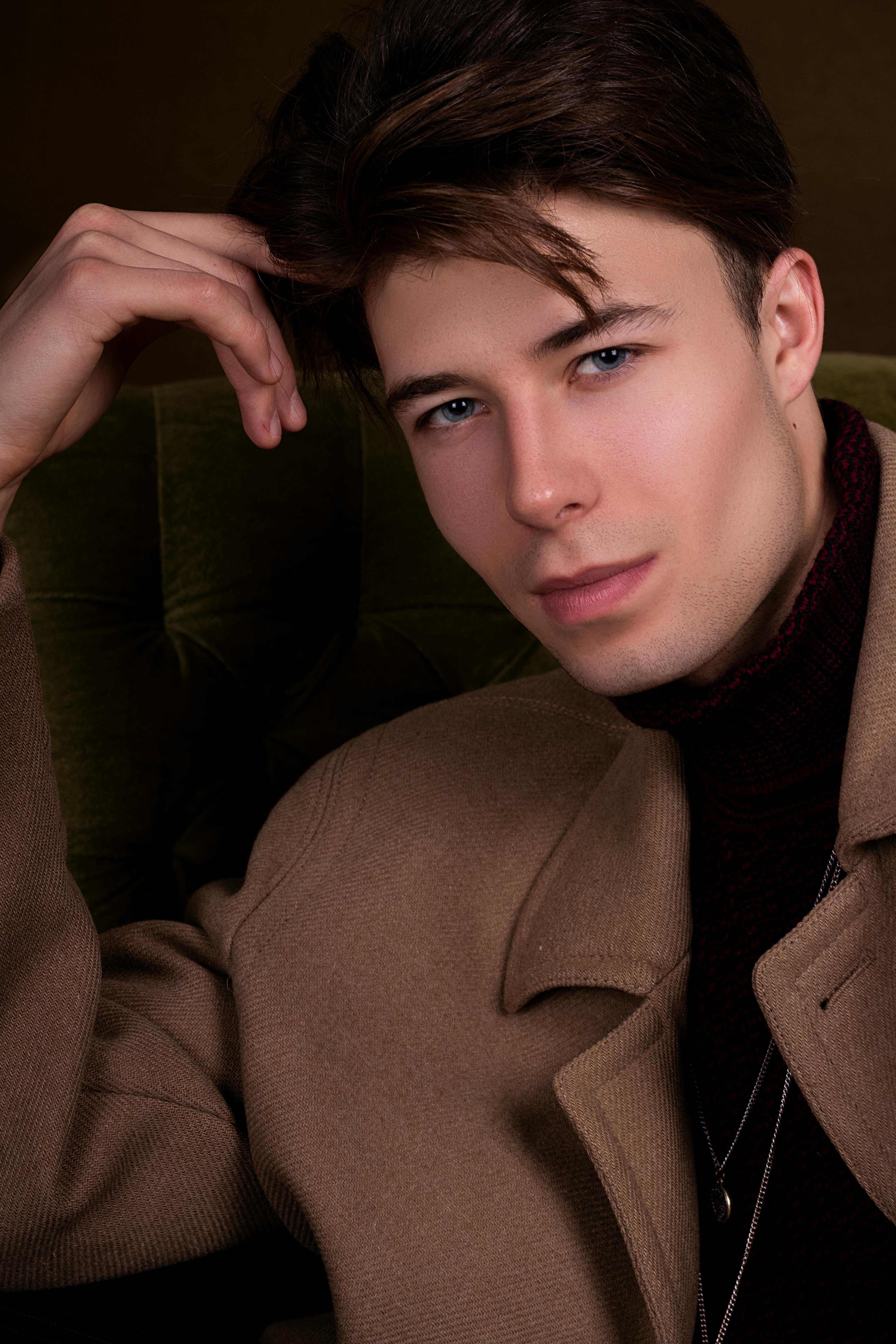 Elegant portrait of a fashionable man in a brown coat, showcasing modern style and charm.
