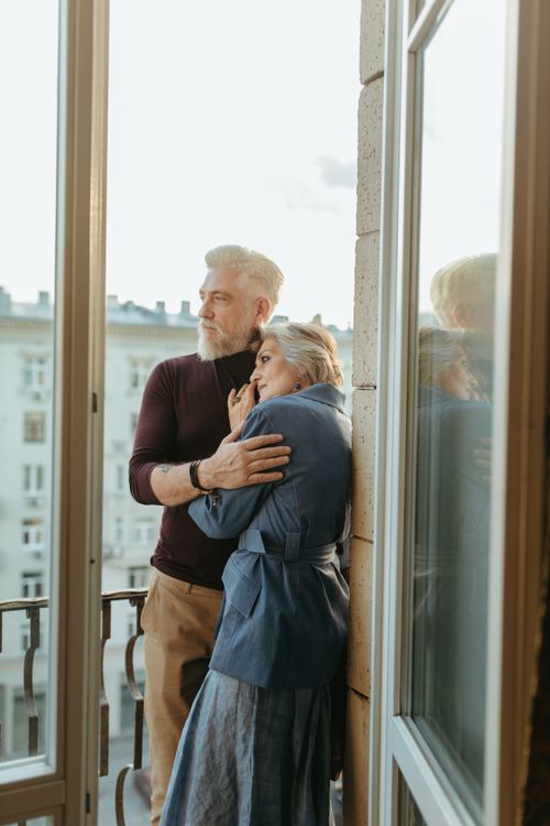 Free Elderly couple sharing a heartfelt embrace on a sunlit balcony, embodying love and connection. Stock Photo