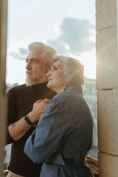 Free A loving senior couple enjoying a tender moment outdoors with the sun setting behind them. Stock Photo