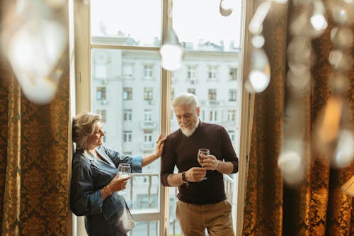 Adult Man and Woman Laughing while Holding Wine Glasses 