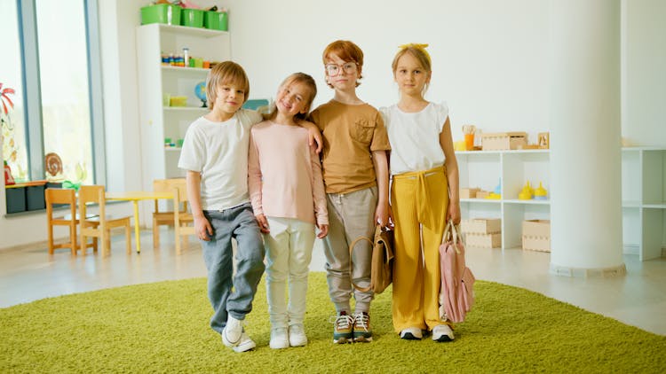 Smiling Children Standing Next To Each Other Inside The Classroom