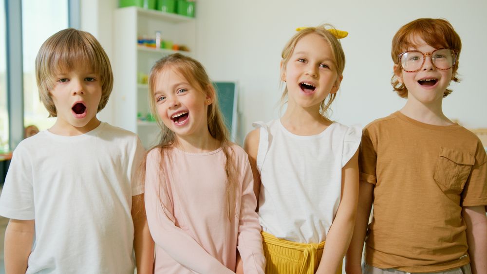 Group of cheerful children smiling and singing together in a bright classroom