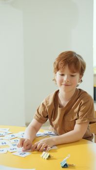 A young boy engaging with letter cards in a bright kindergarten classroom.