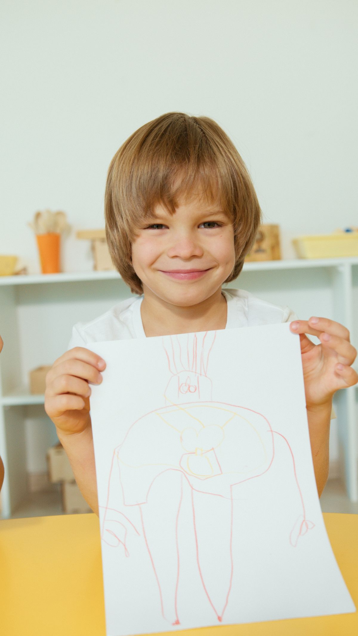 Happy child proudly displaying a colorful giraffe drawing indoors