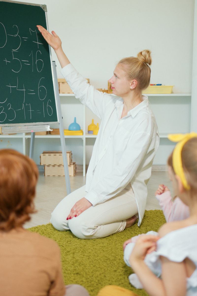 Teacher instructing children with math problems on chalkboard in classroom.
