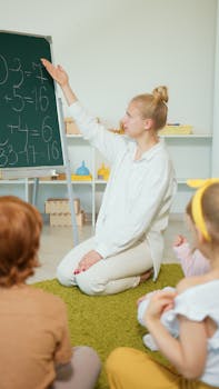 Teacher instructing children with math problems on chalkboard in classroom.