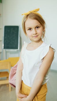 Charming young girl with yellow bow in classroom. Perfect for educational themes.