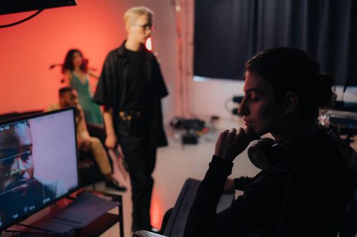 Free Creative professionals collaborating on a dynamic studio set with vibrant lighting. Stock Photo