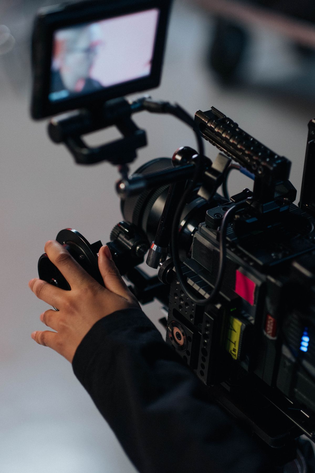 Mâini care reglează o cameră video profesională pe platou, simbol pentru costul unei producții video
