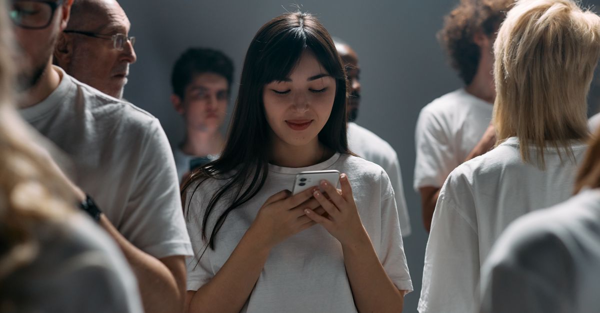 A diverse group of people engaged with their smartphones in a studio setting.