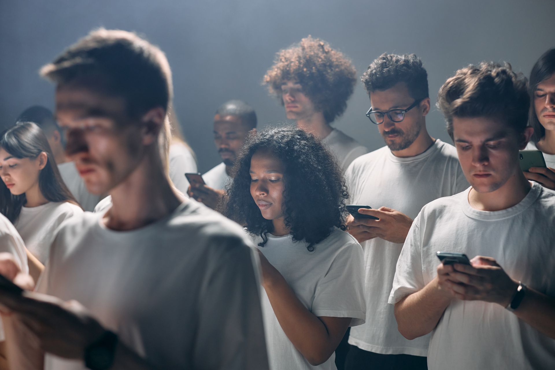 Group of diverse adults focused on smartphones, highlighting modern technology and social connectivity indoors.
