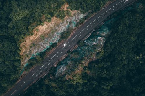 Free Drone shot of a winding road through lush forest in Kijal, Terengganu, Malaysia. Stock Photo