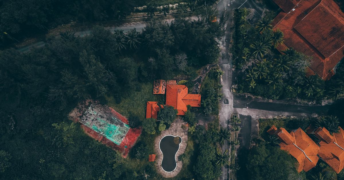 Aerial view of red-roofed houses and pool surrounded by lush greenery in Kijal, Malaysia.