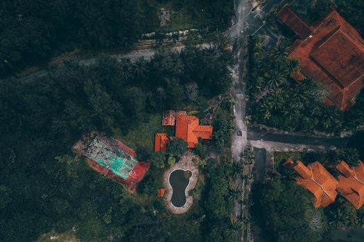 Aerial view of red-roofed houses and pool surrounded by lush greenery in Kijal, Malaysia.
