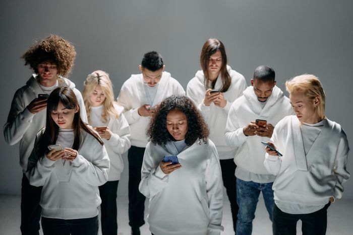 A group of people standing together, each engaged with their phones