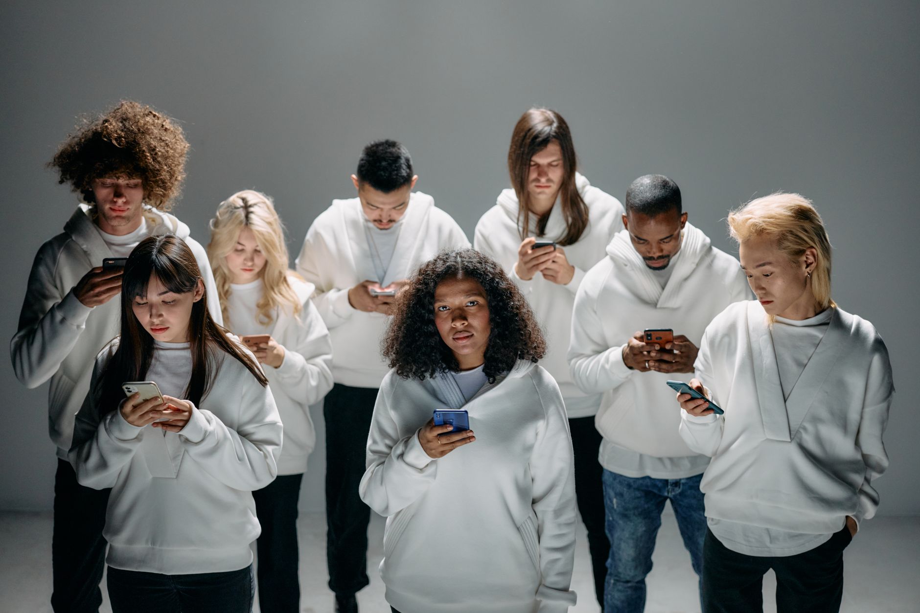 A diverse group of individuals engaged with smartphones, illustrating modern technology and social isolation.