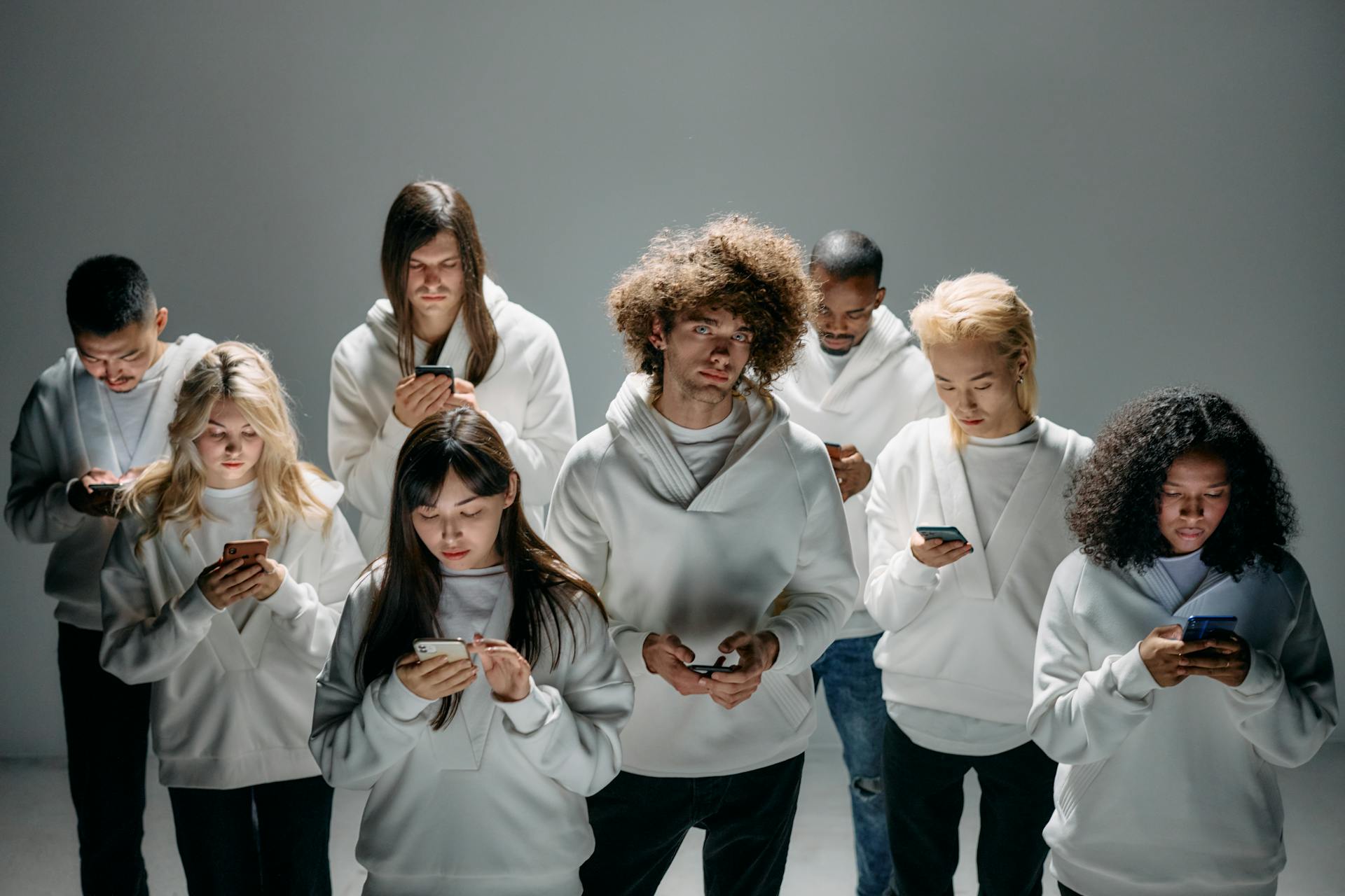 A group of diverse young adults focused on smartphones, symbolizing modern technology and digital connection.