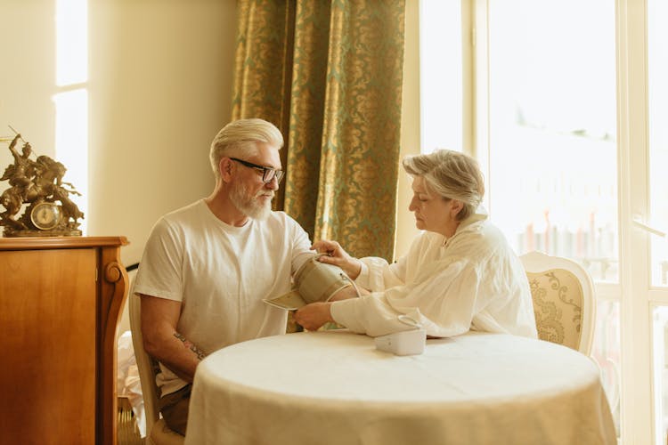 Adult Woman Putting Pressure Cuff On Man's Arm 