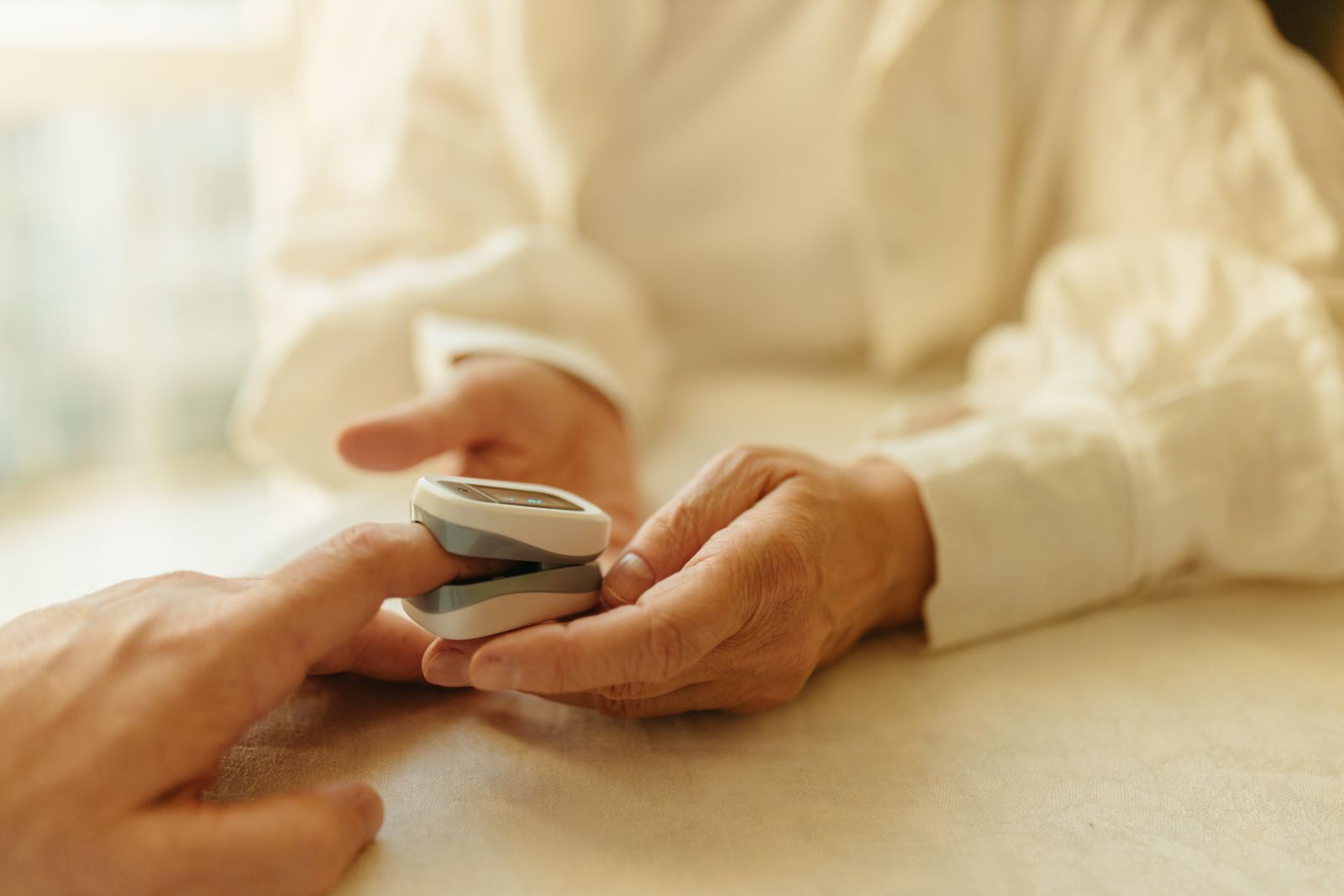 Senior adult using a compact finger wellness monitor during a home health check