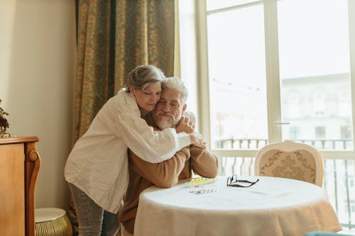 Woman in White Long Sleeve Hugging Man