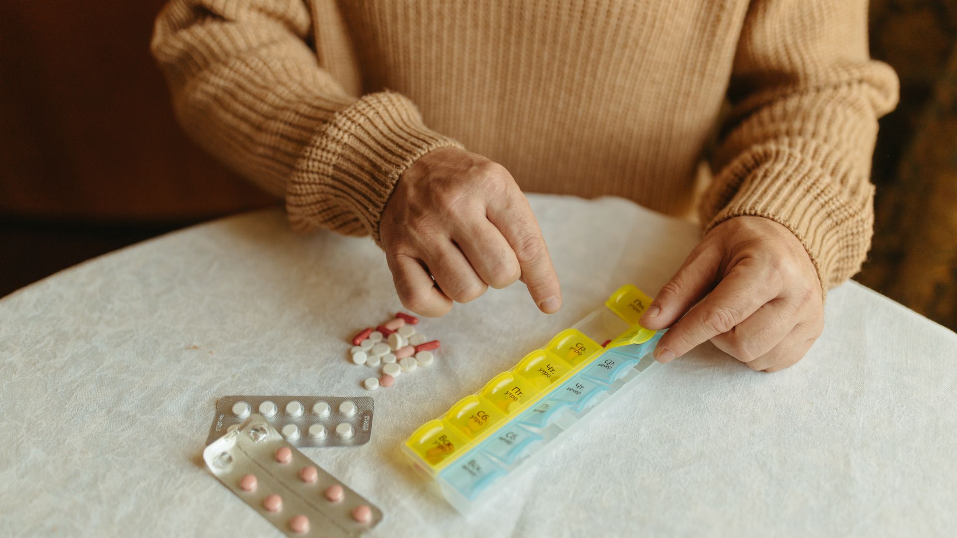 Armodafinil Dosage Guide: Find Your Optimal Dose Senior adult organizing daily medications using a weekly pill organizer on a table indoors — armodafinil dosage guide