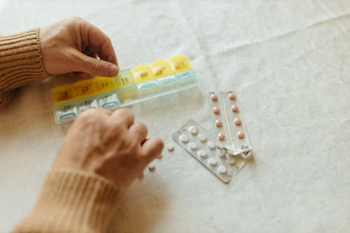 Free Close-Up Shot of a Person Putting Medicines in a Pillbox Stock Photo