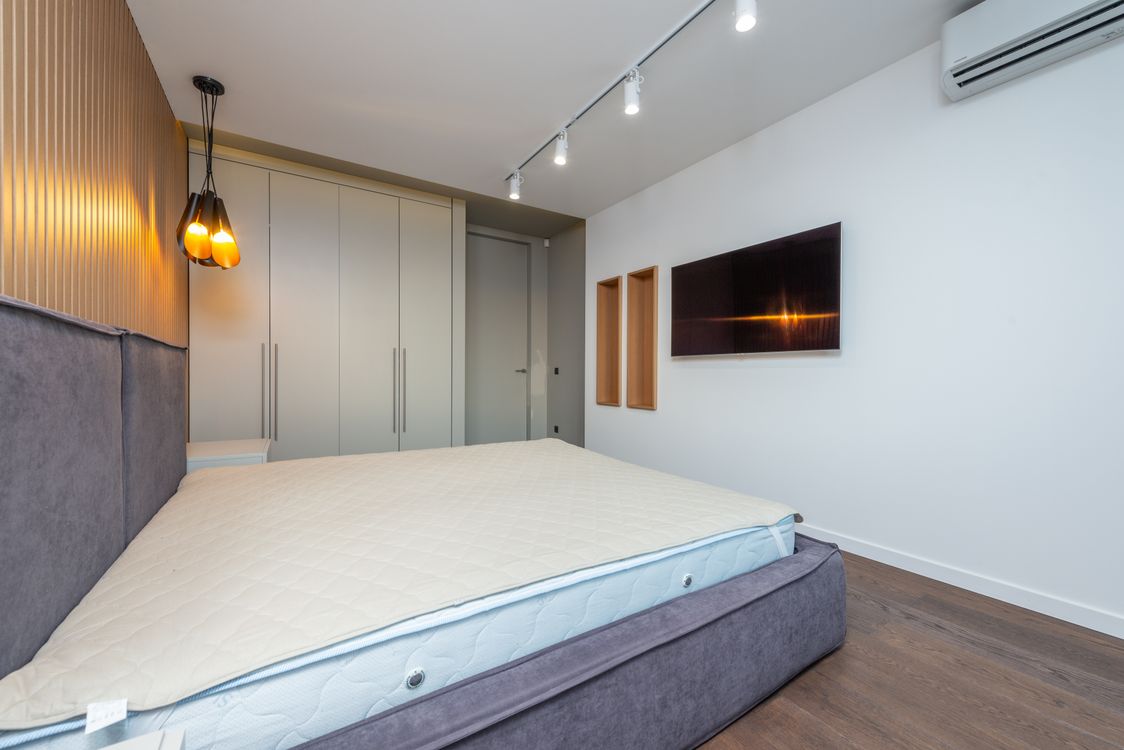 Statement bed with quality mattress and minimal nightstand — proof that one great piece beats seven mediocre ones