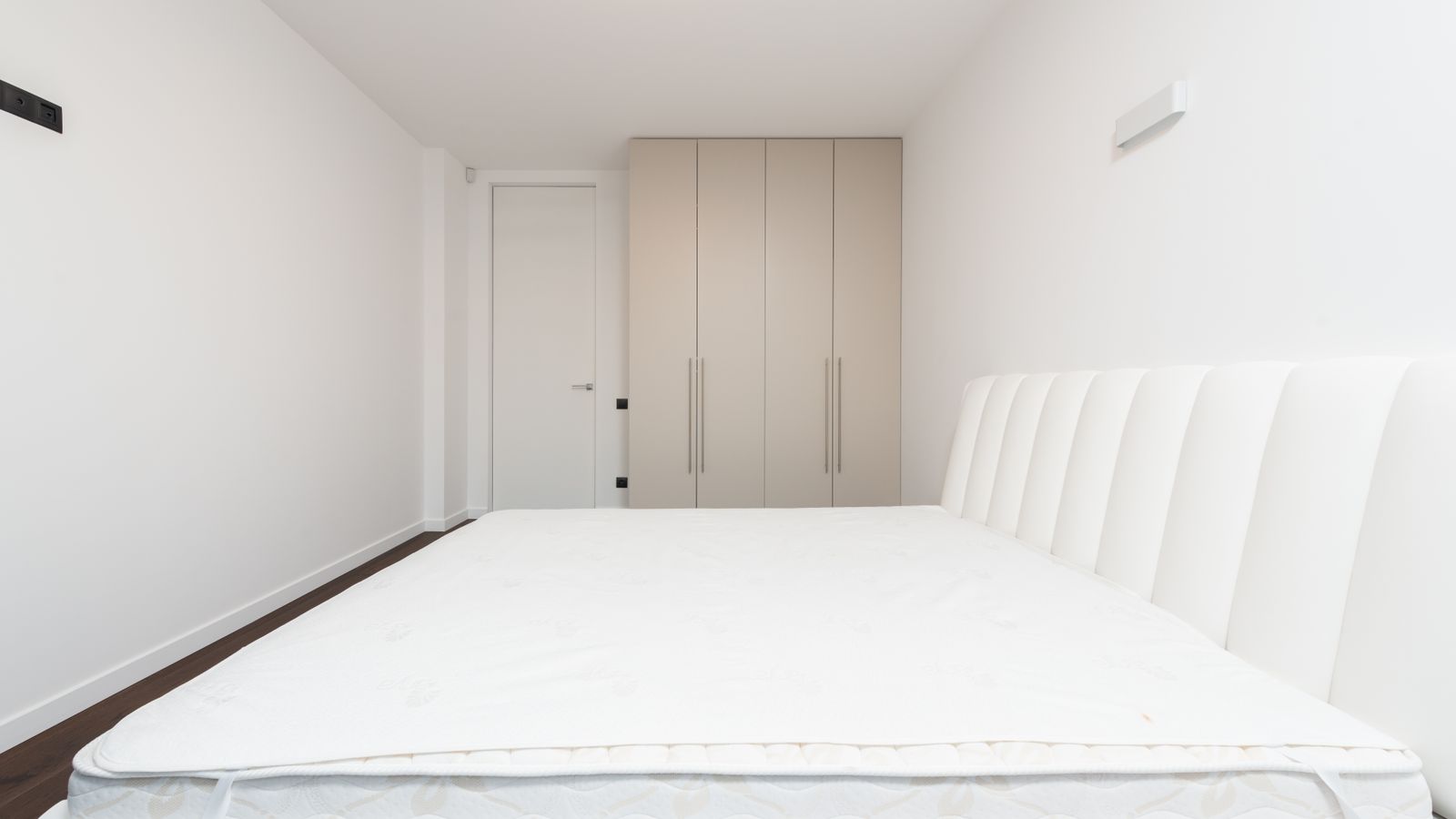 Chambre sobre et vide meublée d'un lit au matelas nu, après traitement et remise en état.