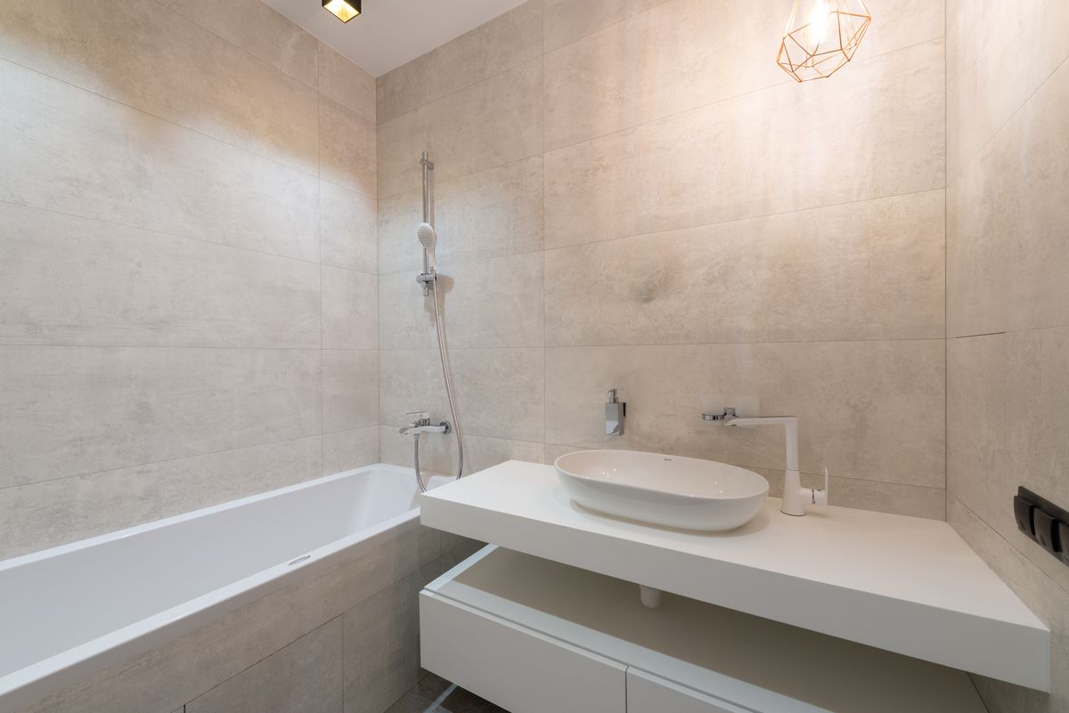 Elegant minimalist bathroom featuring a sleek bathtub and contemporary sink setup. Stock Photo.