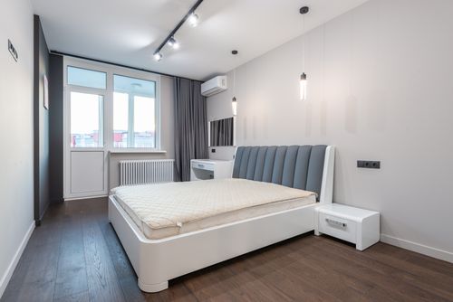 Free Spacious minimalist bedroom featuring modern design elements with white walls and parquet flooring. Stock Photo