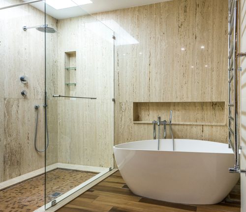 Free Contemporary bathroom featuring a marble wall, glass shower, and stylish bathtub. Stock Photo