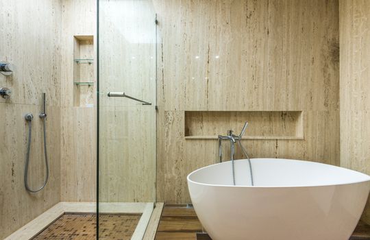 Sleek minimalist bathroom featuring a freestanding bathtub and glass shower with contemporary design.