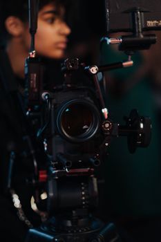 Close-up of a professional cinematic camera setup with a blurred person in the background, capturing focus
