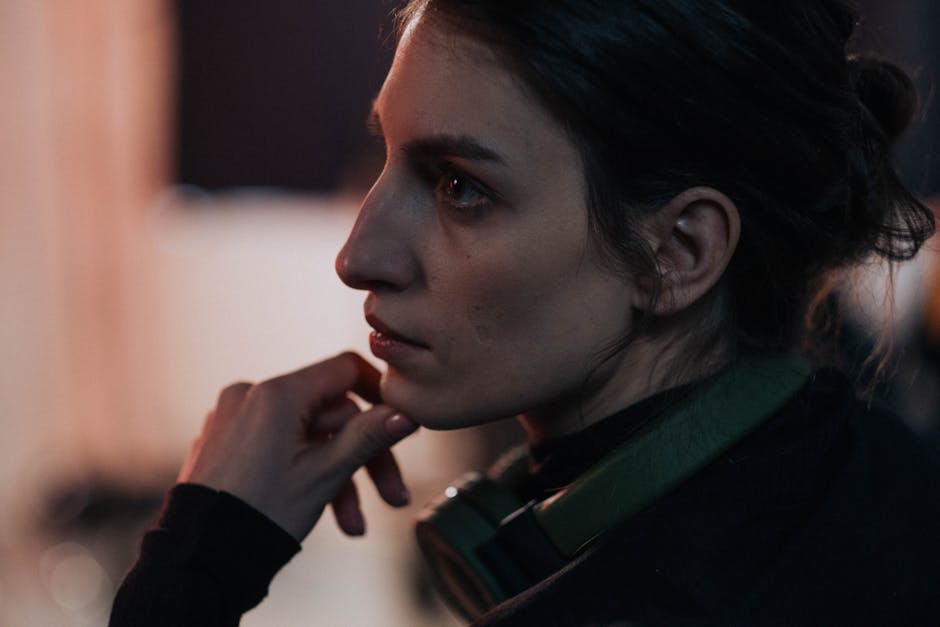 Side profile of a thoughtful woman with headphones in a dimly lit studio.