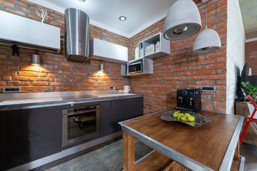 Free Contemporary kitchen interior featuring red brick walls and modern appliances. Stock Photo