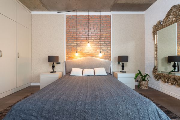Bedroom with a brick accent wall and a blue bedspread
