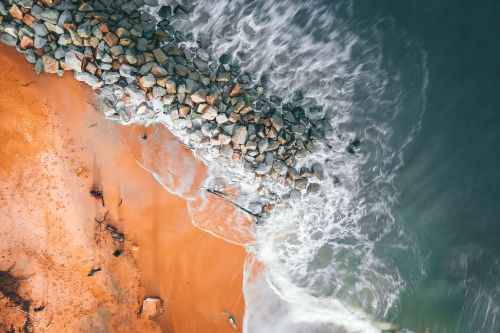 Free Drone shot of rocky coast and waves at a beach in Balok, Malaysia. Serene ocean landscape. Stock Photo