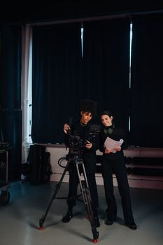 Two crew members in a studio setting working on a film production with camera equipment.
