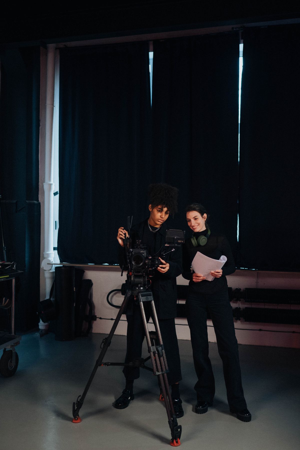 Two crew members in a studio setting working on a film production with camera equipment. Illustrative editorial photograph.
